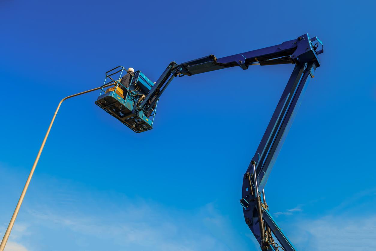 Electrical technician repairing street light by boom lift